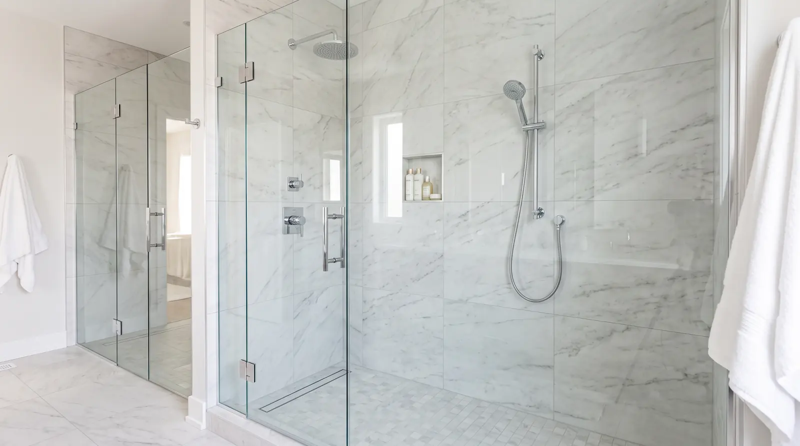 Shower and Tub Plumbing | Prodigy Plumbing & Drain A frameless glass walk-in shower with a rain shower head and a handheld wand, chrome fixtures and large format tile walls