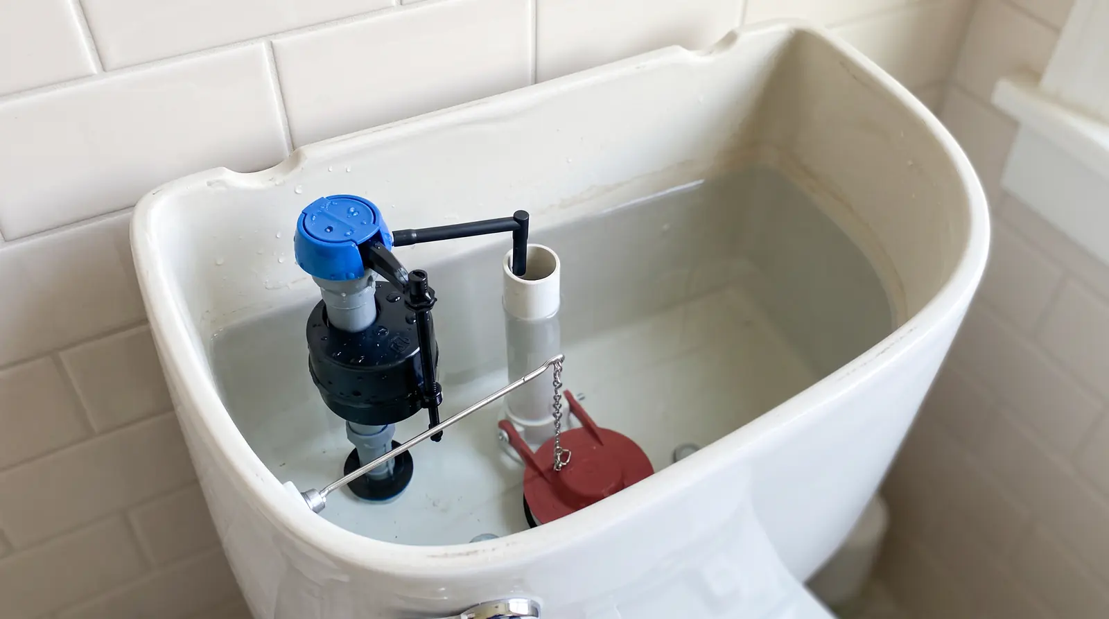 Running and Leaking Toilet Repair | Prodigy Plumbing & Drain The open tank of a clean white toilet showing a new fill valve and flapper, bathroom tile in soft light